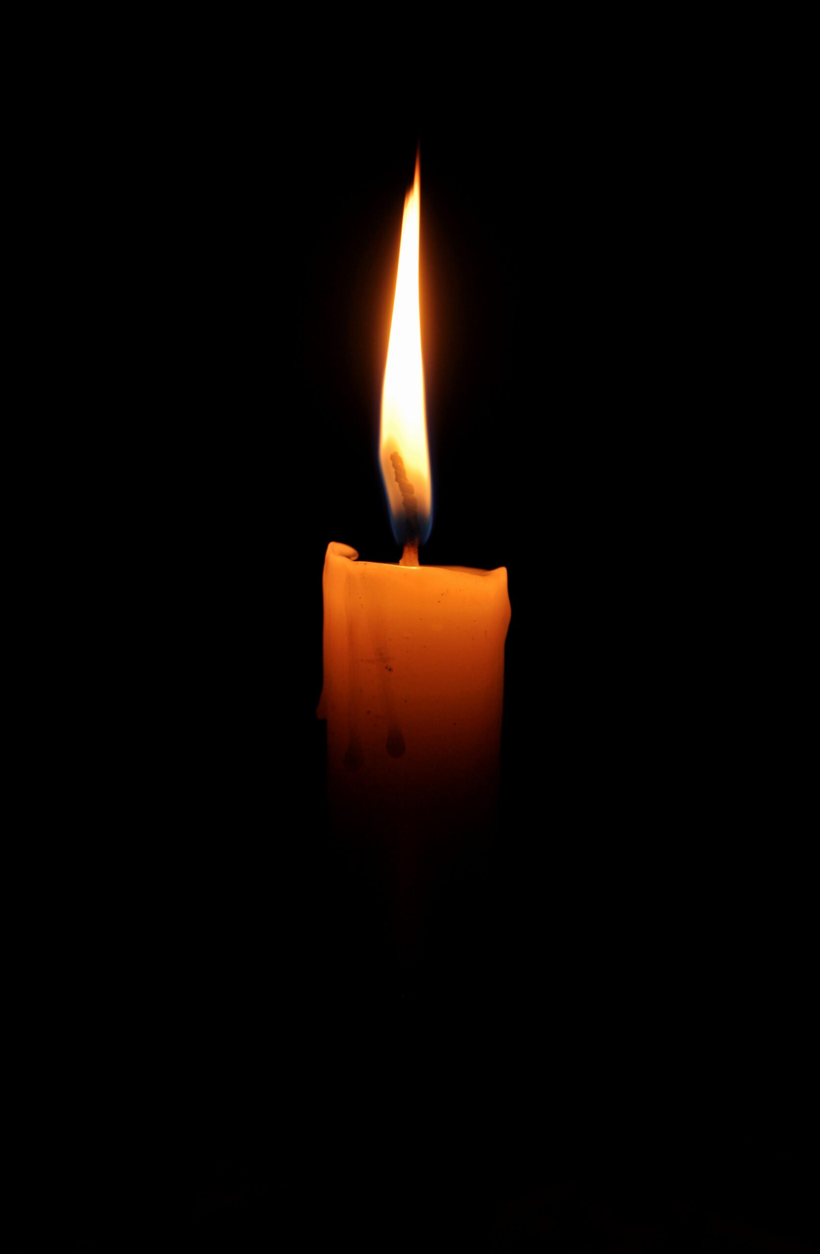 A single lit candle glowing softly in a dark room